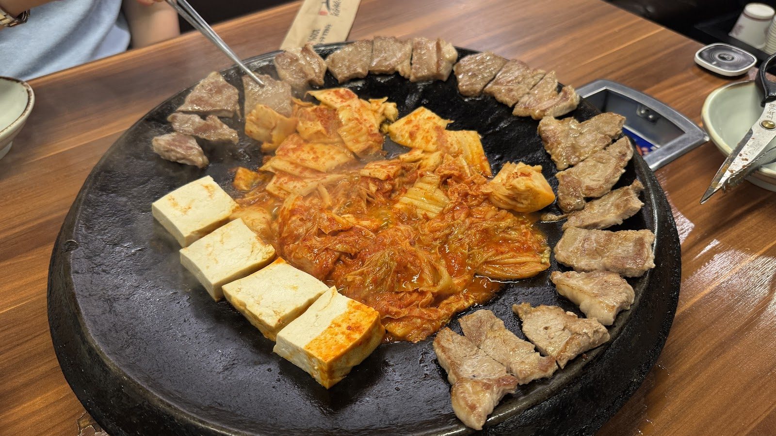불판 가장자리에 둘러 노릇하게 구워진 삼겹살과 가운데의 볶은 김치·두부