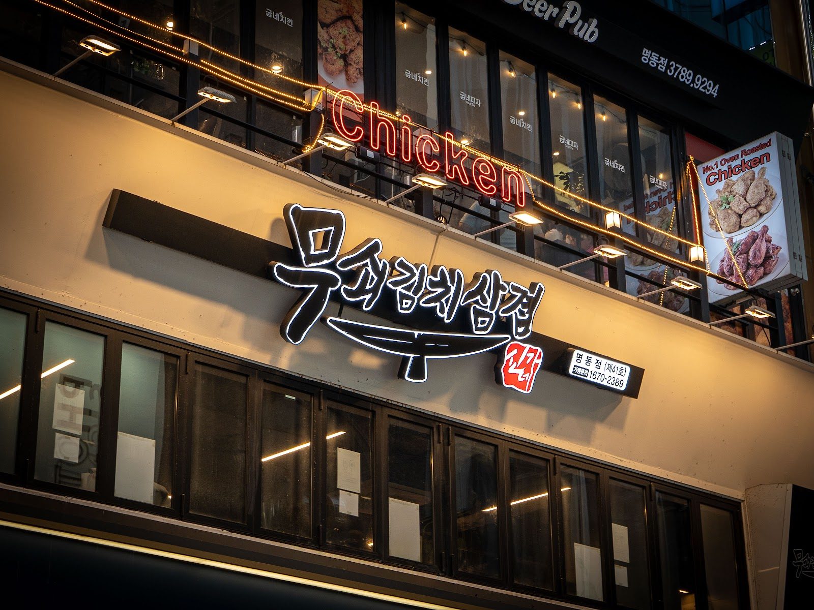 야간에 불을 밝힌 무쇠김치삼겹 명동점 네온 간판과 2층 매장 건물 외관