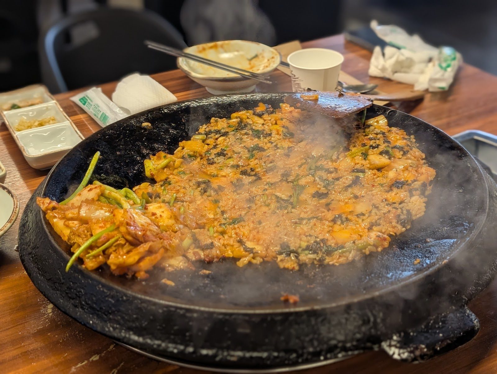 무쇠 불판 위에서 김을 내며 익어가는 김치미나리 볶음밥